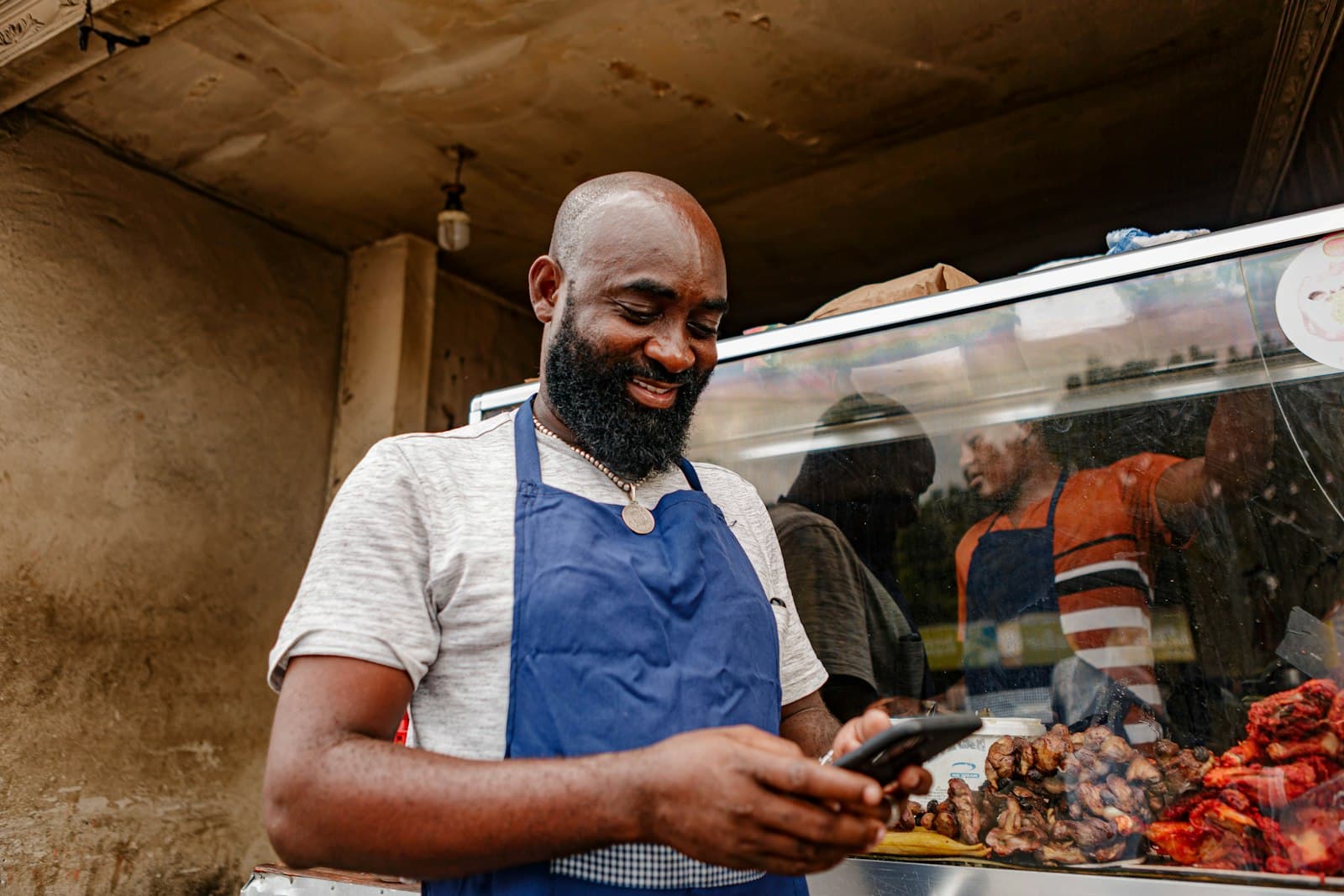A merchant at his food stall confirming a payment on his phone